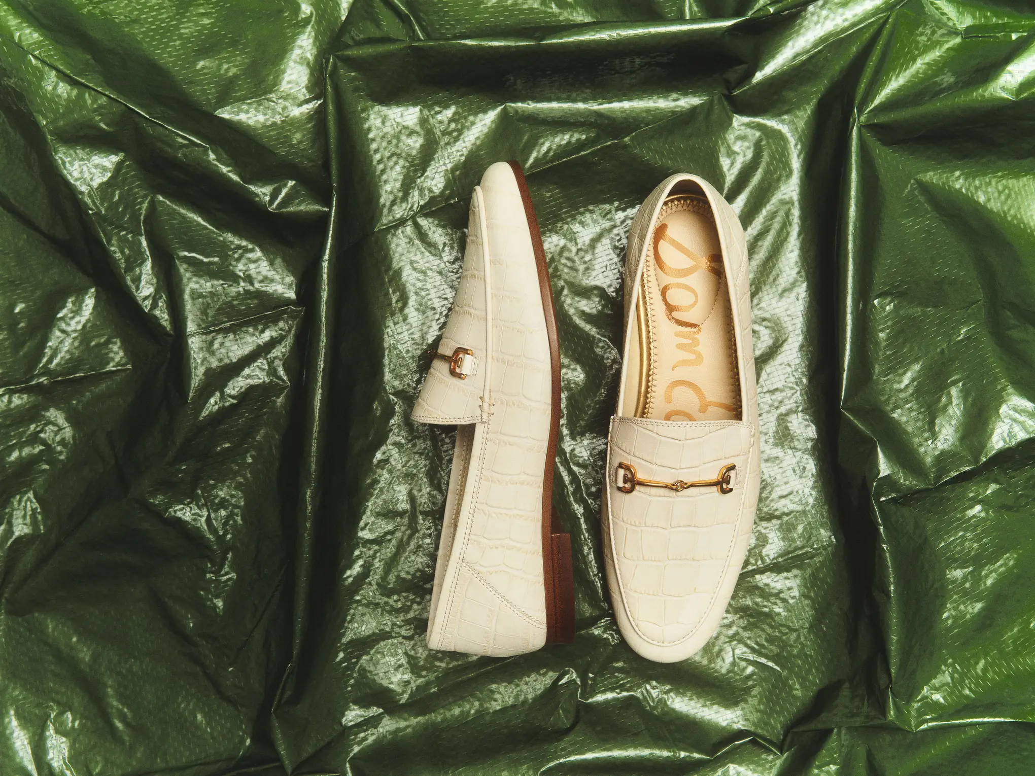Cream loafers with horsebit hardware on green satin