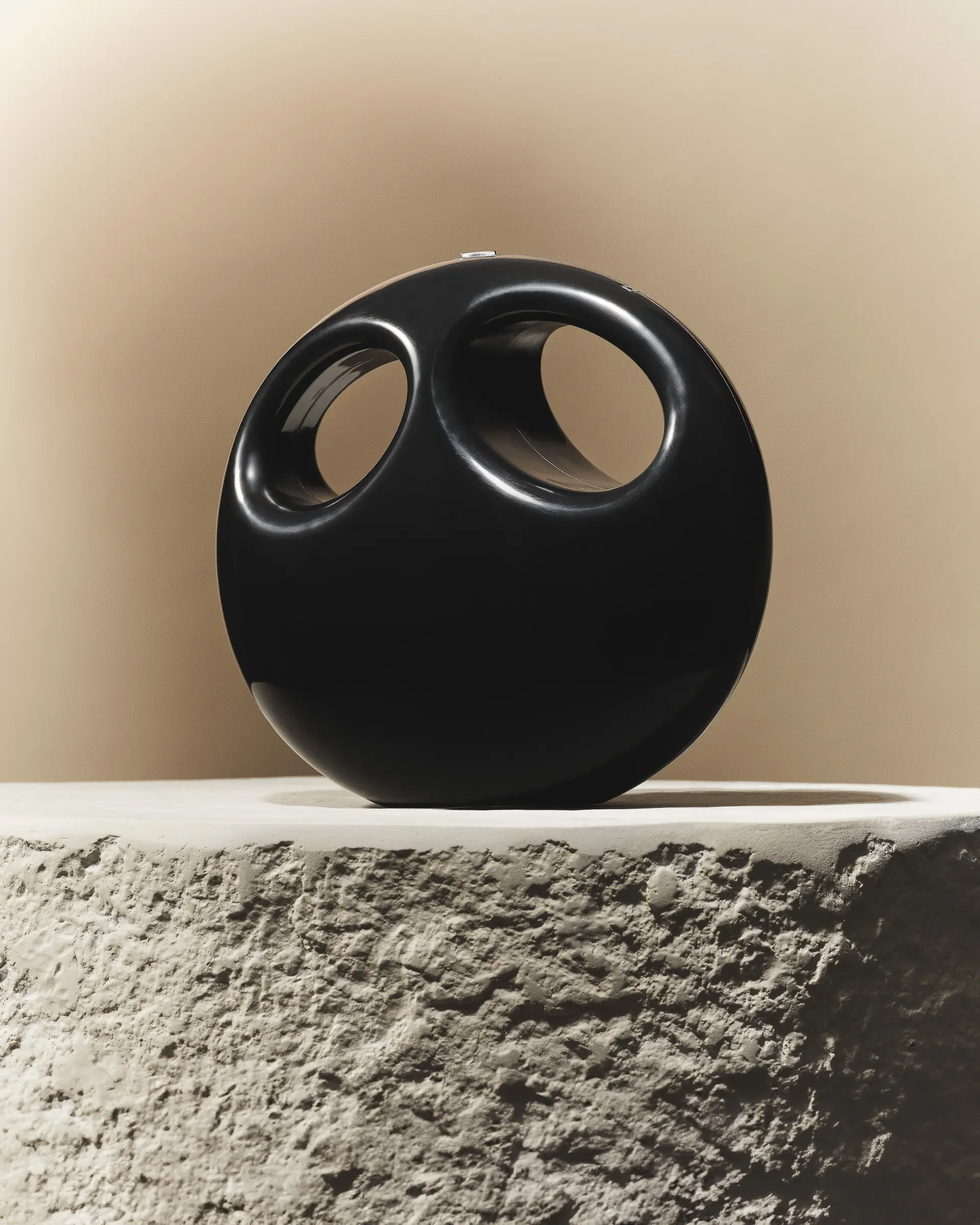 A black sculptural handbag on a stone plinth