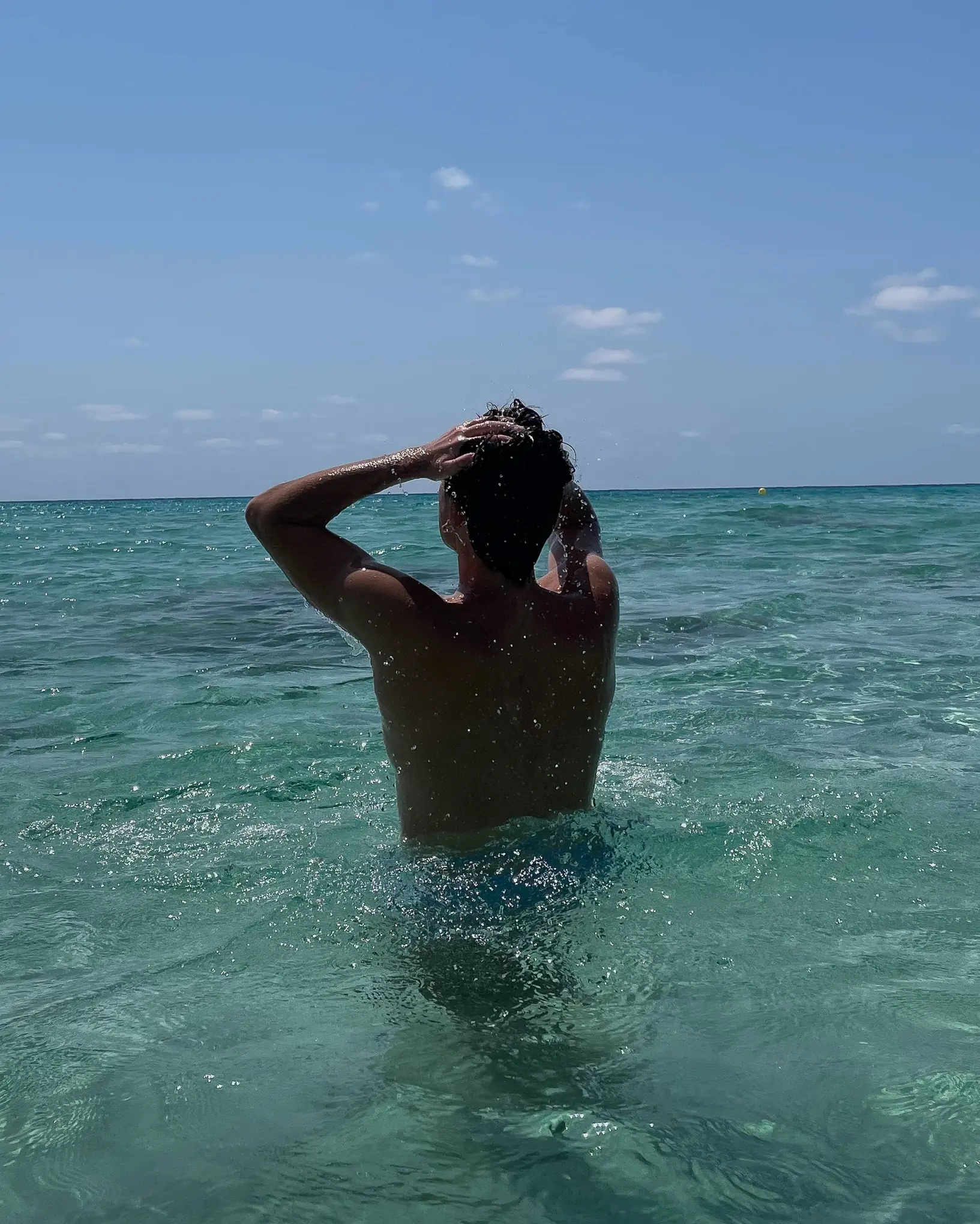 A man wading into turquoise water