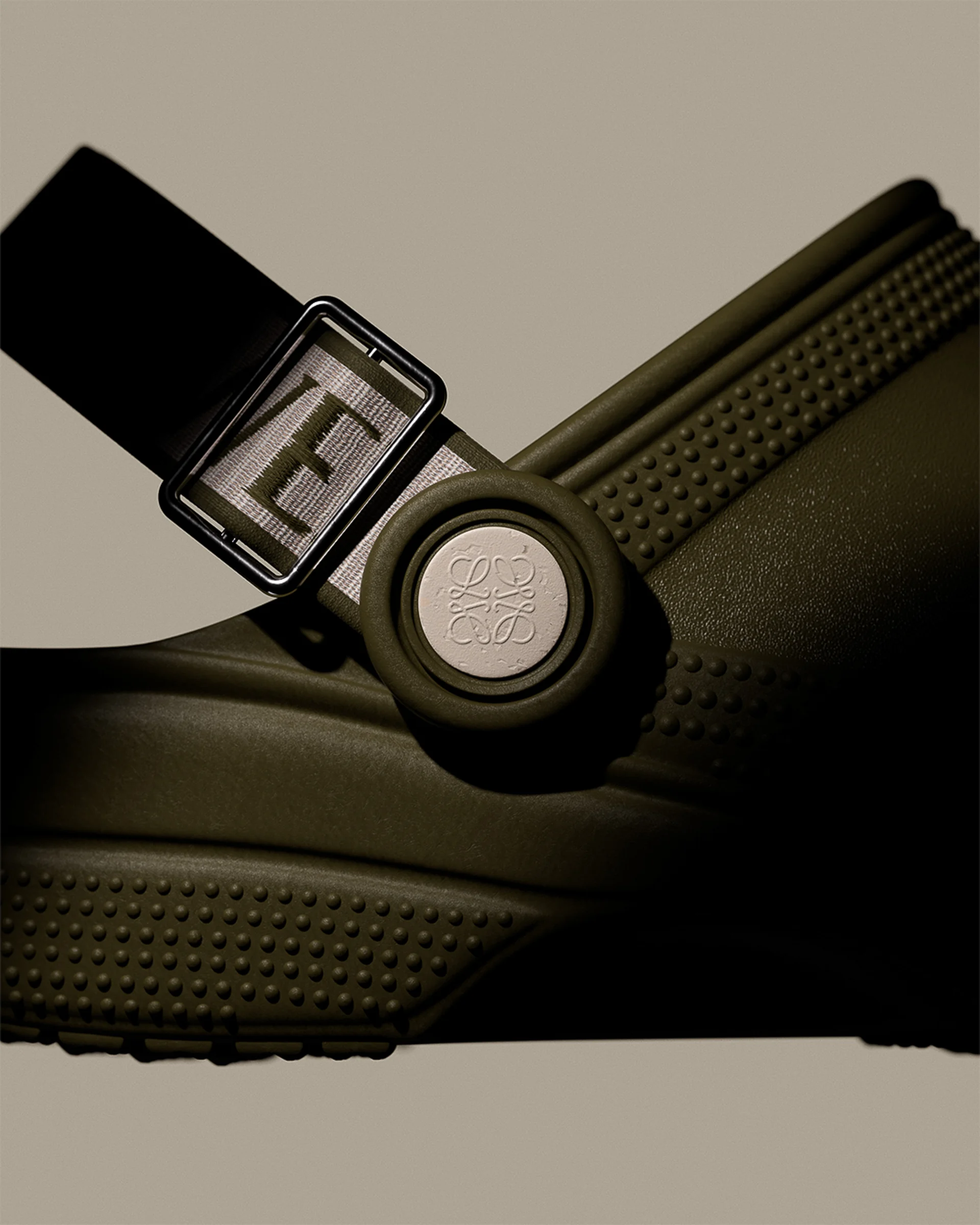 Close-up of an olive sandal with a logo buckle